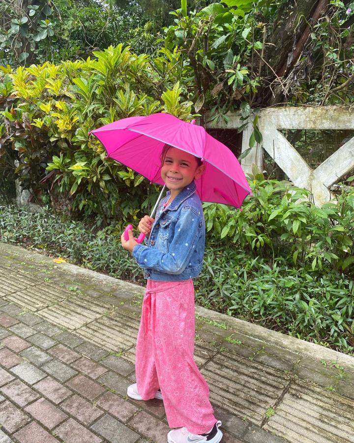 Angelique sonriendo con su paraguas rosa